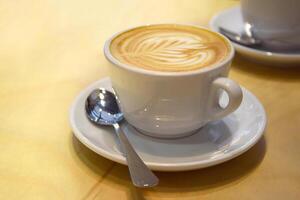 schiuma nel un' tazza di cappuccino su un' leggero di legno tavolo. foto