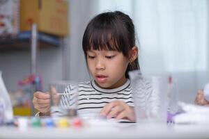 carino poco ragazza fabbricazione Fai da te gesso e pittura a casa. bambini dipingere su gesso sculture con famiglia su vacanza. immaginazione e creatività attività. foto