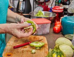 dello chef mani preparare campana peperoni per ripieno con carne nel un' luminosa moderno cucina foto