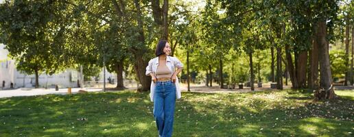 contento asiatico ragazza a piedi nel parco, sensazione la libertà e la gioia, a piedi all'aperto su soleggiato giorno foto