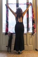 moda donna è guardare su il finestra in piedi insieme con il gatto foto