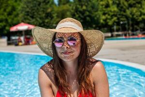 giovane bellissimo donna con cappello e rosso costume da bagno rilassa nel il idromassaggio di nuoto cacca foto