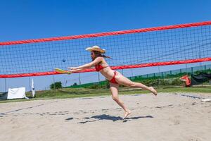 giovane adulto donna giocando tennis su il spiaggia con di legno racchette foto