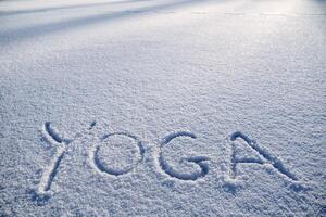 il parola yoga è scritto nel il neve. inverno yoga nel il mattina sole. un' minimalista immagine di zen buddismo. pace e la tranquillità. foto