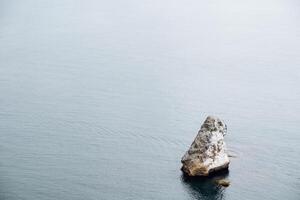 un' roccia su un' capo di il mare. infinito e silenzioso mare superficie. la tranquillità, solitudine e idillio con natura. viaggio per il mare foto