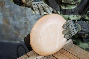 un' legna intaglio maestro ossequi il superficie di un' grande il giro piatto. su il mani di protettivo piatti. legna in lavorazione e creazione di cucina utensili. foto