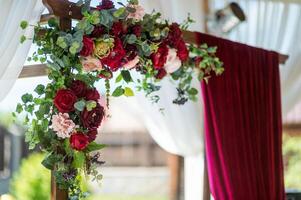 bellissimo fiori decorato su il nozze arco su il sfocato sfondo. romantico design di un' nozze arco fatto di Borgogna stoffa e fiori. foto