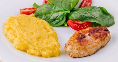 polenta con cotoletta e ciliegia pomodori con basilico foto