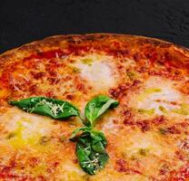 margherita Pizza con basilico su nero pietra foto