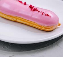 eclairs con rosa Smalto su un' bianca piatto foto