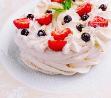 Pavlova torte con crema e fresco frutti di bosco su piatto foto