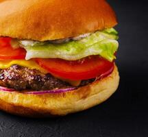 appetitoso hamburger al formaggio su nero pietra avvicinamento foto