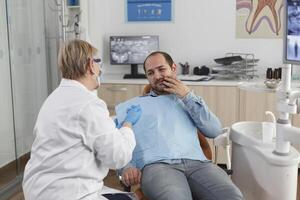 dentista medico spiegando orale igiene per paziente con mal di denti discutere assistenza sanitaria trattamento durante stomatologiche consultazione nel dentale ufficio camera. concetto di medicina servizio foto