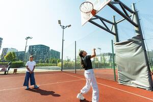 bambini e gli sport. adolescenziale ragazza giocando pallacanestro su il terreno di gioco. foto