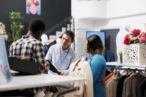 africano americano acquirente controllo di moda camicia, chiede boutique lavoratore di tessuto. elegante coppia guardare a grucce con nuovo collezione, shopping per alla moda Abiti nel moderno Al dettaglio memorizzare foto