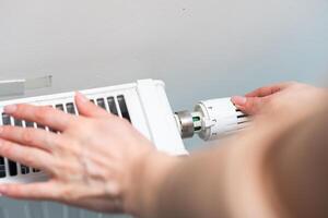 calore termosifone pomello. donna mano regolazione temperatura su riscaldamento termosifone foto