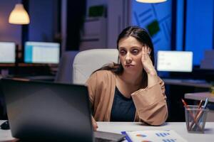 stanco imprenditore provando concentrato guardare a Come tanto opera ha per essere fatto per un' Scadenza. inteligente donna seduta a sua posto di lavoro nel il corso di in ritardo notte ore fare sua lavoro. foto