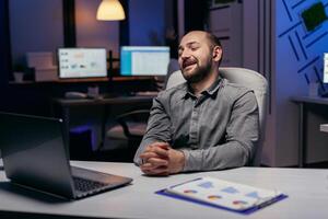 finanziario specialista discutere di statistica durante in linea chiamata utilizzando il computer portatile e senza fili cuffia. uomo d'affari nel il corso di un importante video conferenza mentre fare col tempo a il ufficio. foto