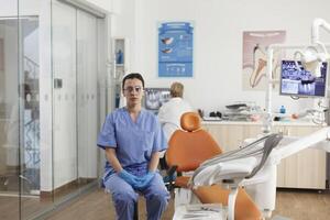 ritratto di stomatologo assistente Lavorando a stomatologiche trattamento nel odontoiatria medico ufficio durante odontoiatria visita medica. medico squadra analizzando denti radiografia. medicina Servizi foto