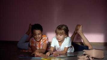 famiglia, tempo libero e infanzia concetto - contento sorelle dire bugie su pavimento e fare compiti a casa a casa foto