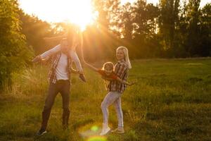 contento famiglia madre padre e bambino figlia su natura su tramonto foto
