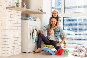 contento famiglia uomo padre capofamiglia e bambino figlia nel lavanderia con lavaggio macchina foto
