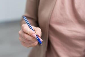 utilizzando un' mano hold il penna per scrivere. foto