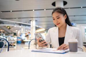 asiatico donna libero professionista godere Lavorando e parlando su mobile Telefono a bar e persone Lavorando a partire dal dovunque su digitale dispositivo e senza fili tecnologia.giovane donna d'affari analizzando documenti foto