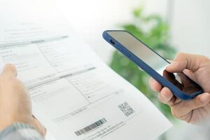 attività commerciale uomo uso Telefono per scansione codice a barre o qr codici per pagare credito carta conto dopo ricevente documento fattura in linea. pagamento, ricevere, pagare elettricità, digitale pagamenti senza i soldi, tecnologia foto