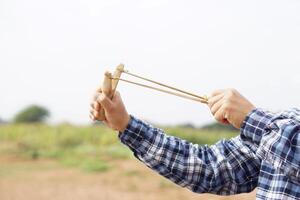 vicino su mani hold di legno fionda per giocando tiro gioco. concetto , tailandese tradizionale arma quello uso per sparare uccelli, pesce , per combattimento gioco o altro scopi. foto