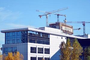 alto salire edificio sotto costruzione. installazione di bicchiere facciata pannelli su un' rinforzata calcestruzzo struttura. foto