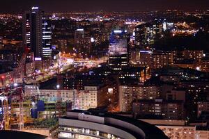 Visualizza di a notte bicchiere edifici e moderno attività commerciale grattacieli. Visualizza di moderno grattacieli e attività commerciale edifici nel centro. grande città a notte. foto