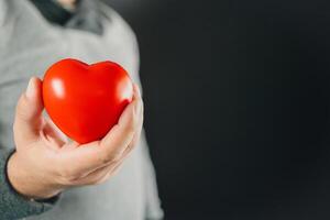 bene Salute e assicurazione concetto. umano mano Tenere rosso cuore. foto