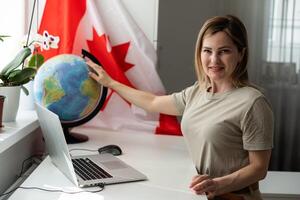 bellissimo sorridente donna coperto nel canadese bandiera guardare a telecamera isolato su bianca foto