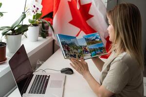 bellissimo sorridente donna coperto nel canadese bandiera guardare a telecamera isolato su bianca foto