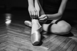 giovane ballerina seduta, gambe e d'oro scarpe. classico arte concetto. preparazione per danza. avvicinamento. nero e bianca foto