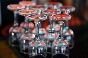 Due righe di vino bicchieri In piedi sottosopra giù su il bar a il bar. avvicinamento foto