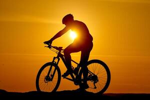 silhouette di un' bicicletta su cielo sfondo su tramonto su un' montagna superiore. foto