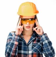 contento giovane donna è indossare arancia sicurezza casco, giallo bicchieri e scacchi camicia guardare a il telecamera. Isoalted sfondo. avvicinamento. foto