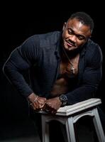 bello muscolare uomo pendente su sedia a nero sfondo. attraente forte afro uomo in posa per telecamera. foto