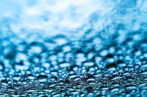 fantastico Visualizza di chiaro grande e piccolo gocce di pioggia su un' bicchiere su blu sfondo. realistico puro acqua goccioline condensato per creativo design. macro tiro foto