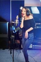 giovane femmina cantante registrazione album nel il professionale studio. donna cantando un' canzone nel musica registrazione studio. foto