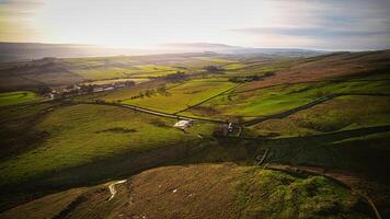 aereo Visualizza di un' lussureggiante verde campagna con rotolamento colline, campi, e un' piccolo strada sotto un' chiaro cielo a sicomoro spacco, Northumberland, UK. foto