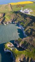 aereo Visualizza di un' aspro costa con un' faro, blu mare, e verde i campi sotto un' chiaro cielo nel Flamborough, Inghilterra foto