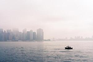 un' piccolo pesca barca su il superiore baia su il sfondo inferiore Manhattan nel il nebbia foto