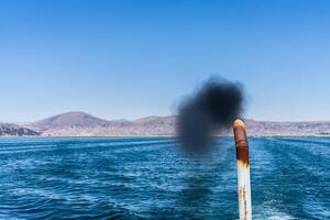 pennacchio un' nero fuliggine In arrivo a partire dal il coda tubo di un' turista barca su lago titicaca foto