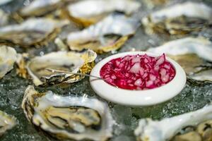 freschi ostrica servito tavolo con Ostriche, cipolla e Ghiaccio. salutare mare cibo di fresco Ostriche nel ghiaccio e cipolla nel piccolo ciotola. avvicinamento foto