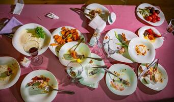 superiore Visualizza di sporco piatti e bicchieri dopo un' pasto su il ristorante tavolo. il avanzi cibo su sporco piatti dopo cena. foto