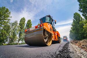 strada riparazione, compattatore stabilisce asfalto. pesante speciale macchine. asfalto finitrice nel operazione. lato Visualizza. avvicinamento. foto