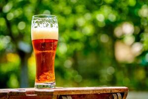 bicchiere di leggero birra su il di legno tavolo. bolle e schiuma nel un' bicchiere di leggero birra foto